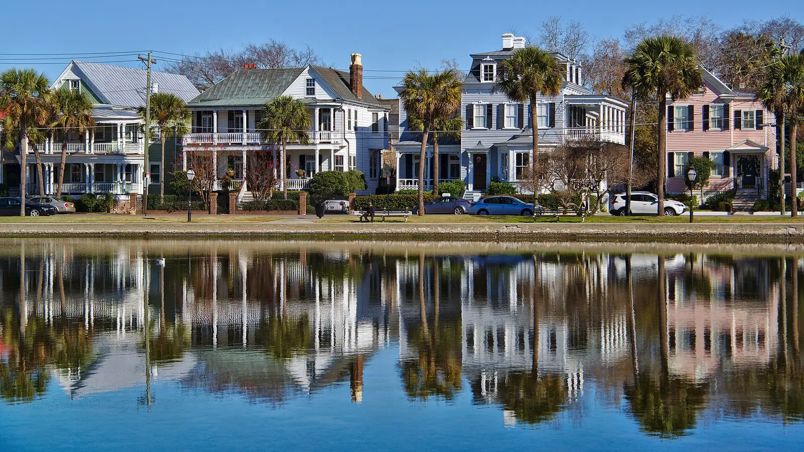 Houses along Colonial Lake reflected in the water, where the city's Light the Lake celebration opens the holiday season and the parade route begins.