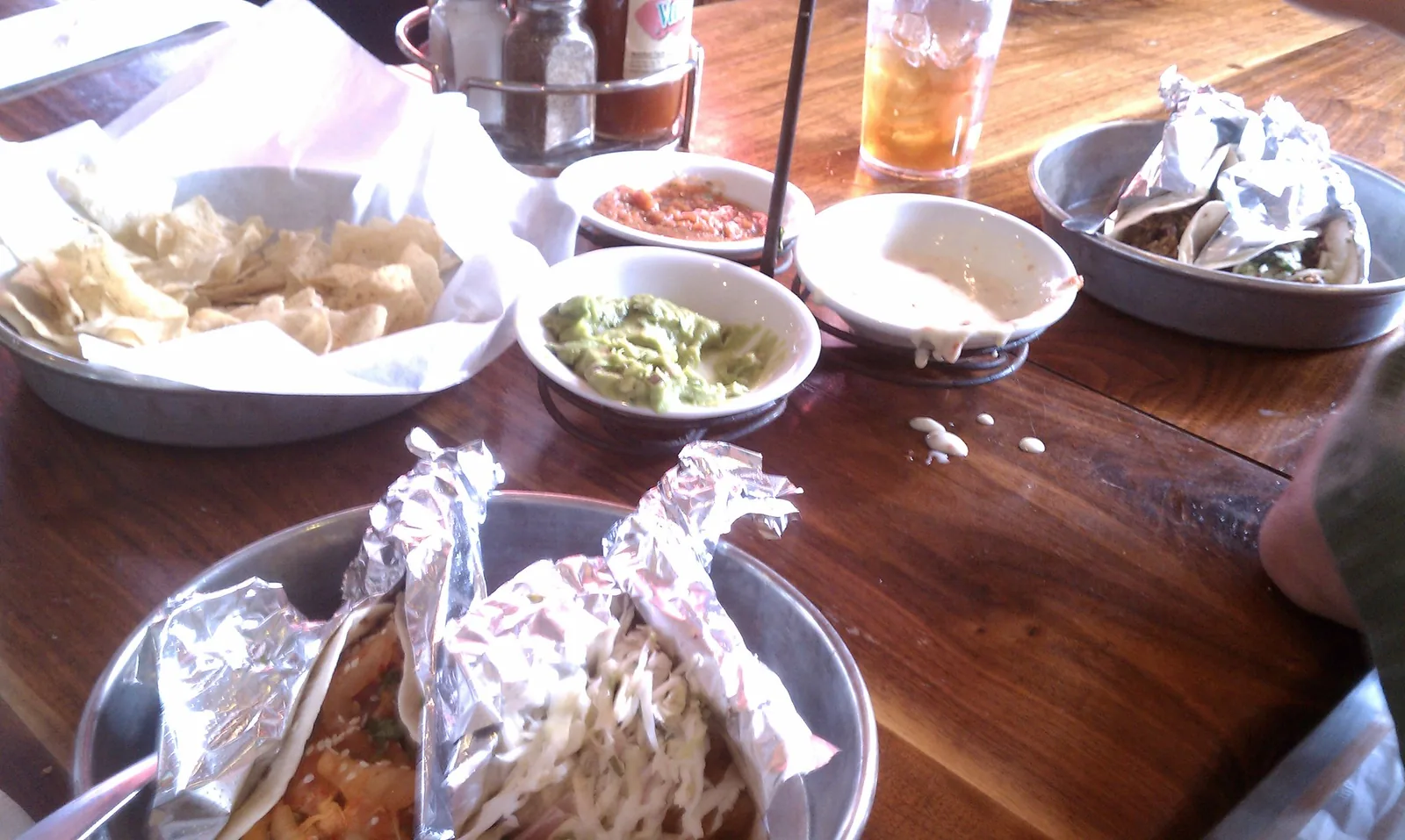 Tacos in foil, chips, salsa and guacamole on a table at Taco Boy in the Charleston area.