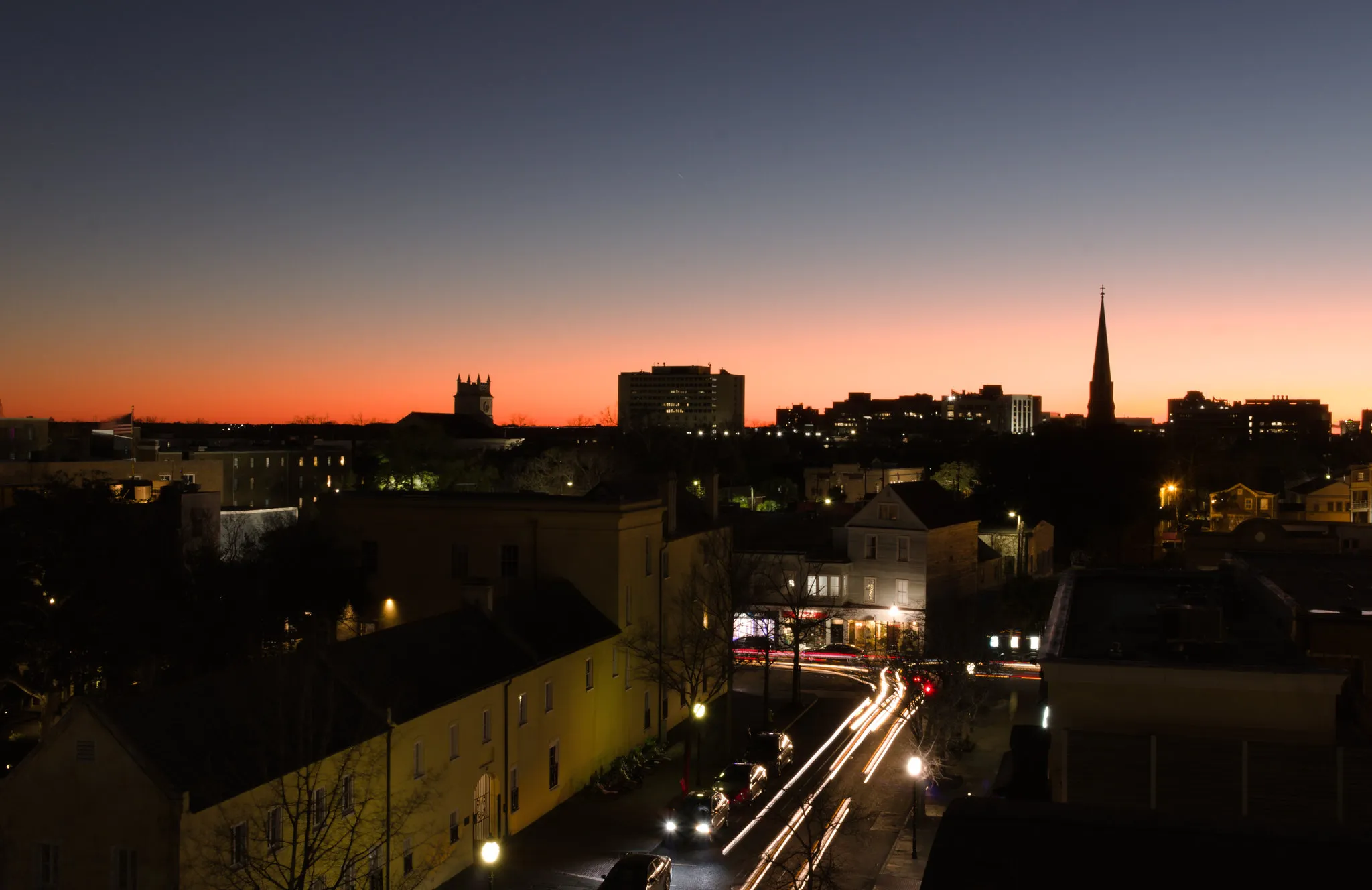 Car lights streak along a street below the Charleston peninsula skyline at dusk, seen from the Visitor Center garage.